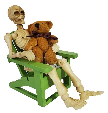 Skelett sitzt im grünen Liegestuhl und hält einen Teddybär