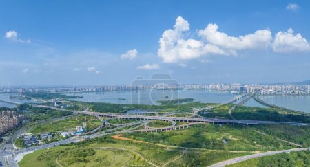 Photo for Aerial view of lake and city skyline with interchange overpass against a blue sky, Jiujiang city, Jiangxi province, China - Royalty Free Image