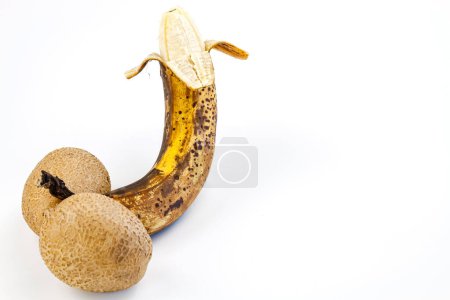 Reife Banane mit braunen Flecken auf weißem Hintergrund.