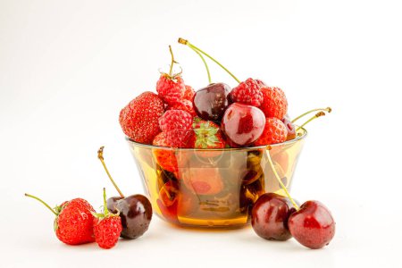 Foto de Una mezcla de apetitosas frutas rojas pequeñas en un tazón. Enfoque selectivo con profundidad de campo poco profunda. - Imagen libre de derechos