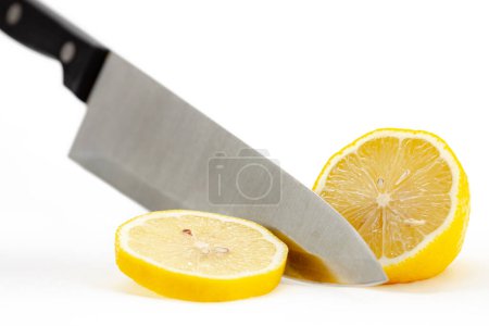 Foto de Cortar rodaja redonda de limón con cuchillo en aislado sobre fondo blanco. Enfoque selectivo con profundidad de campo poco profunda. - Imagen libre de derechos