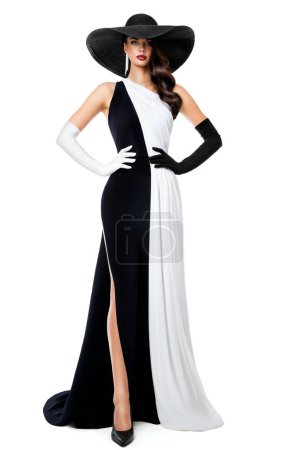 Foto de Mujer Vestido formal en blanco y negro. Modelo de moda en vestido de contraste de noche larga. Elegante dama de sombrero negro y guantes sobre fondo aislado. Concepto de Reina de Ajedrez - Imagen libre de derechos