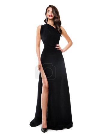 Photo for Happy Woman in Black Long Dress. Fashion Model in Evening Gown with Slit over White Background. Smiling Elegant Lady with Holiday Wavy Hair style and Glamour Makeup - Royalty Free Image