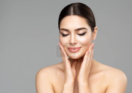 Beauty Face Skin Care. Woman with Full Lips Natural Makeup over isolated background. Beautiful Model enjoying Spa Massage. Facial Plastic Surgery and Dermal Filler Cosmetology