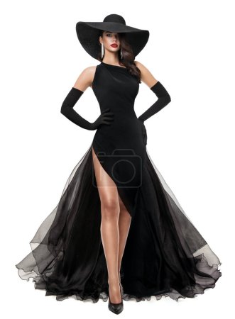 Foto de Mujer de moda en vestido de noche negro aislado blanco. Elegante Lady en Sombrero de Verano Negro y Largo Vestido de Lujo con Raja. Hermosa chica bien vestido - Imagen libre de derechos