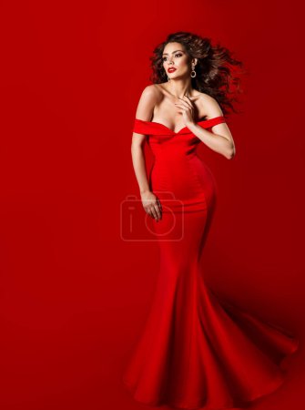 Téléchargez les photos : Femme élégante en robe rouge longue. Modèle de mode en robe de soirée en soie. Belle fille avec bouclé coiffure noire agitant sur le vent - en image libre de droit