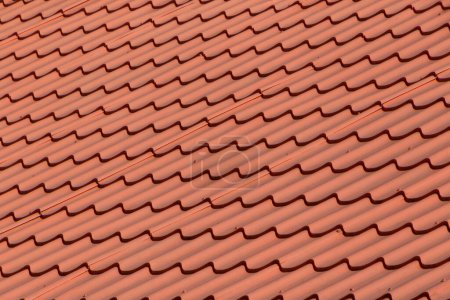 texture abstraite : gros plan du toit de la maison recouvert de tuiles métalliques rouges