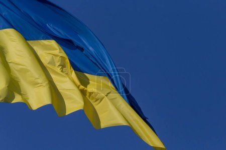 Téléchargez les photos : Gros plan du drapeau ondulé de l'Ukraine contre un ciel bleu clair - en image libre de droit