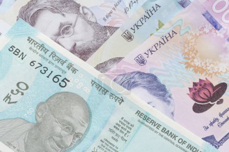 Téléchargez les photos : Près de cinquante billets de banque en roupie indienne couchés sur des billets de banque ukrainiens hrivnya - en image libre de droit