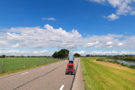 Photo for Man in Dutch landscape on bike with doggy trailer - Royalty Free Image