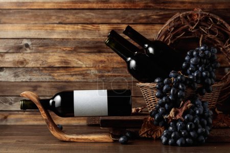 Foto de Red wine and blue grapes. Wine and grapes in a vintage setting. On a bottle empty label. Copy space. - Imagen libre de derechos