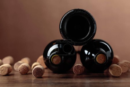 Photo for Unopened bottles of red wine and wine corks on a wooden table. Copy space. - Royalty Free Image