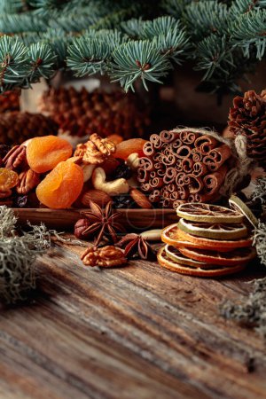 Téléchargez les photos : Fruits secs et noix sur une vieille table en bois. Nature morte de Noël avec agrumes séchés, abricots, raisins secs, noix diverses, bâtonnets de cannelle et anis. - en image libre de droit