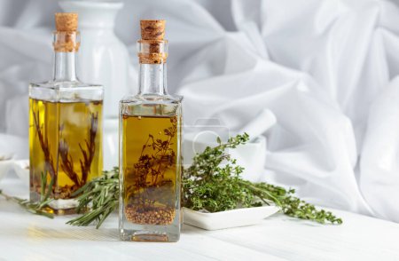 Photo for Bottles of olive oil with spices and herbs on a white wooden table. Copy space. - Royalty Free Image