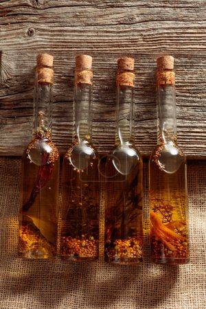 Foto de Aceite de oliva casero con hierbas y especias en botellas pequeñas. - Imagen libre de derechos