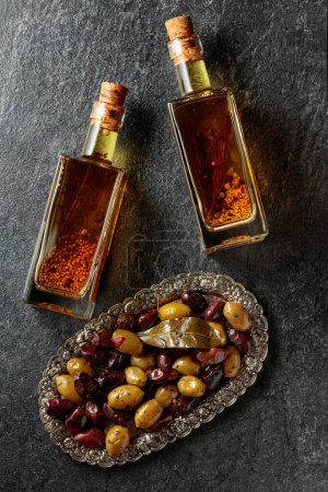 Foto de Spicy olives and olive oil on a black stone table. Top view. - Imagen libre de derechos
