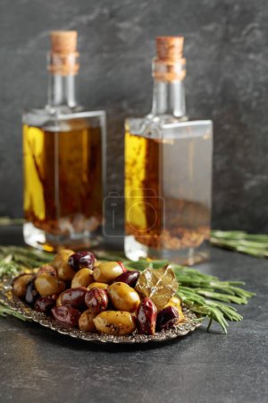 Téléchargez les photos : Spicy olives and bottles of olive oil. on a black stone table. - en image libre de droit