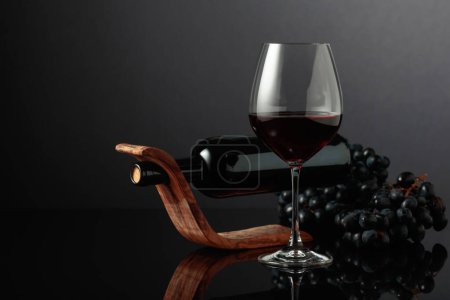 Téléchargez les photos : Red wine and blue grapes on a black reflective background. - en image libre de droit