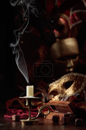 Foto de Se acabó el juego. Bodegón con una vela apagada, dados y máscaras de carnaval en una vieja mesa de madera. - Imagen libre de derechos