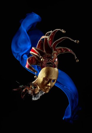 Foto de Máscaras de carnaval antiguas sobre un fondo negro con aleteo de tela azul. - Imagen libre de derechos