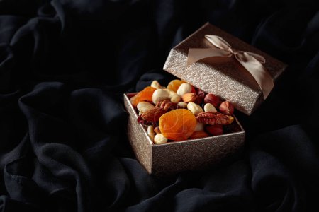 Photo for Dried fruits and nuts in a gift box on a black cloth. - Royalty Free Image