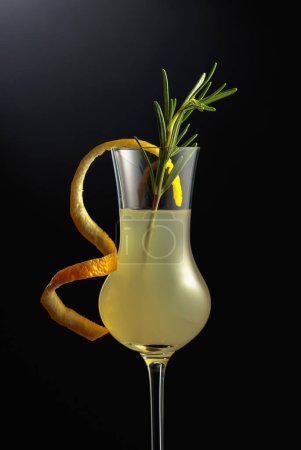 Foto de Limoncello en vaso, licor de limón italiano dulce, bebida alcohólica fuerte tradicional adornada con cáscara de limón y romero. - Imagen libre de derechos