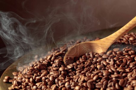 Téléchargez les photos : Les grains de café moyennement torréfiés sont fumés dans une rôtissoire. Espace de copie. - en image libre de droit
