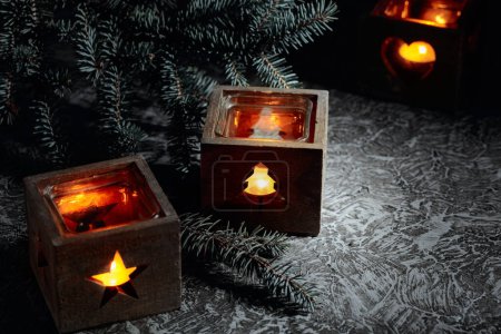 Foto de Decoración de Navidad. Velas ardientes en pequeñas cajas de madera sobre una mesa vintage. - Imagen libre de derechos