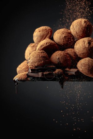 Photo for Delicious chocolate truffles sprinkled with cocoa powder on a black background. - Royalty Free Image