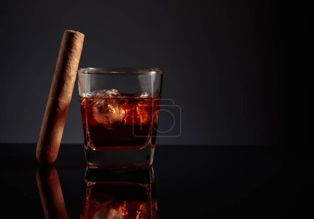 Photo for Whiskey with ice and cigar on a black reflective background. - Royalty Free Image