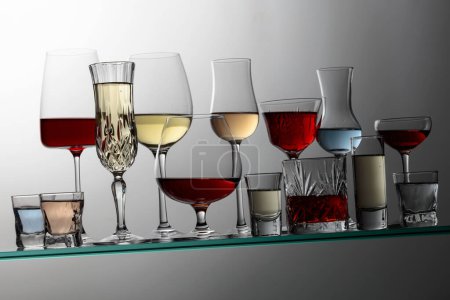 Téléchargez les photos : Various alcoholic drinks in a bar on a tilted glass shelf. - en image libre de droit