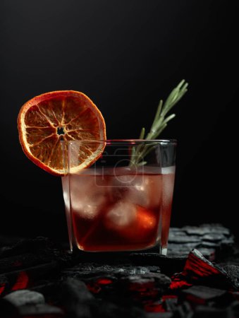 Foto de Cóctel a la antigua con whisky, hielo, rebanada de naranja seca y romero. - Imagen libre de derechos