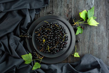 Photo for Black currant with leaves on a old wooden table. Top view. - Royalty Free Image