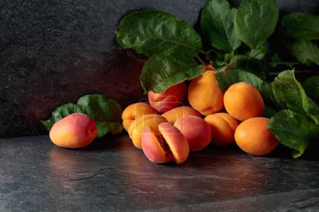 Photo for Apricots with leaves on a black stone table. - Royalty Free Image