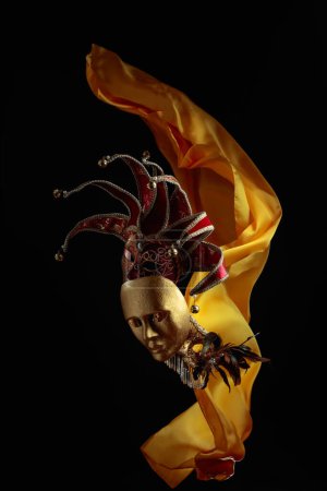 Foto de Máscaras de carnaval antiguas sobre un fondo negro con aleteos de tela amarilla. - Imagen libre de derechos
