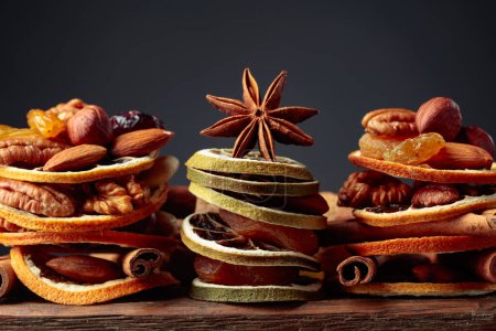 Téléchargez les photos : Nature morte de Noël avec des fruits secs, des noix et des épices sur une vieille table en bois. Espace de copie. - en image libre de droit
