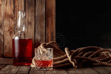 Foto de Cristal y botella con ron, coñac o whisky sobre un fondo de madera viejo. - Imagen libre de derechos