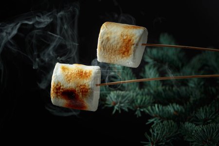 Téléchargez les photos : Guimauves grillées avec de la fumée sur le fond d'un arbre de Noël. - en image libre de droit