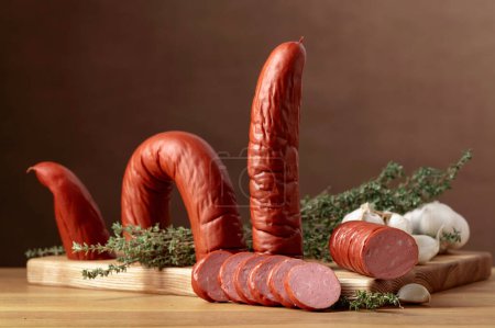 Photo for Smoked sausage with thyme and garlic on a wooden table. - Royalty Free Image