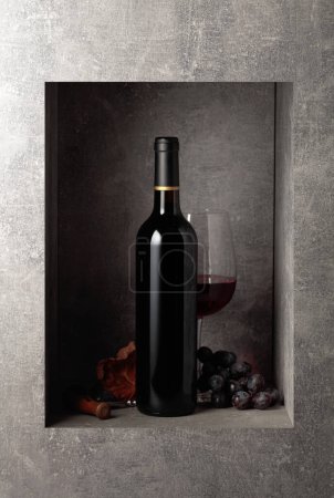 Téléchargez les photos : Bottle and glass of red wine with blue grapes. Copy space. - en image libre de droit