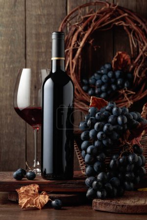 Foto de Red wine and blue grapes. Wine and grapes in a vintage setting on an old wooden table. - Imagen libre de derechos