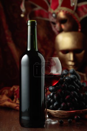 Photo for Still life with red wine, grapes, and vintage carnival masks. - Royalty Free Image
