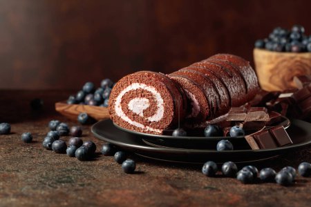 Photo for Chocolate roll cake with blueberries and a broken black chocolate bar. - Royalty Free Image