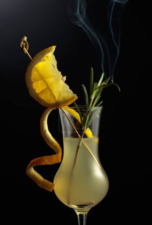 Photo for Limoncello in a glass. A sweet Italian lemon liqueur, a traditional strong alcoholic drink garnished with a steaming rosemary branch. - Royalty Free Image