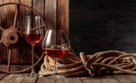 Téléchargez les photos : Snifters au rhum, cognac ou whisky sur un vieux fond de bois. Espace de copie. - en image libre de droit