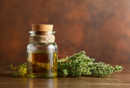 Photo for Bottle of thyme essential oil with fresh thyme on an old wooden table. Copy space. - Royalty Free Image