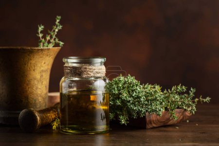 Foto de Botella de aceite esencial de tomillo con tomillo fresco sobre una vieja mesa de madera. Copiar espacio. - Imagen libre de derechos