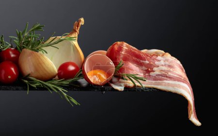 Téléchargez les photos : Bacon fumé aux œufs, tomates, oignons et romarin. Espace de copie. - en image libre de droit