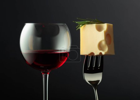 Téléchargez les photos : Verre de vin rouge et fromage Maasdam avec romarin sur fond noir. - en image libre de droit