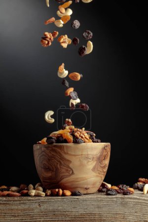 Foto de Frutos secos voladores y nueces. La mezcla de nueces y pasas en un tazón de madera. - Imagen libre de derechos